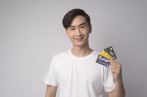 Young asian man holding credit card over white background studio, shopping and finance concept. photo