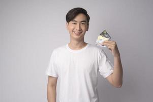 Young asian man holding credit card over white background studio, shopping and finance concept. photo