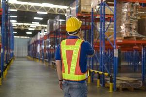 Young asian male worker wearing helmet using talki walki in modern warehouse. photo