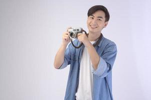 Young happy asian tourist man over white background studio, travel and holidays concept. photo