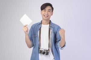 Young happy asian tourist man over white background studio, travel and holidays concept. photo