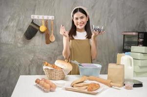 joven hermosa mujer está horneando en su negocio de cocina, panadería y cafetería foto