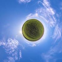 Little planet transformation of spherical panorama 360 degrees. Spherical abstract aerial view in field with awesome beautiful clouds. Curvature of space. photo