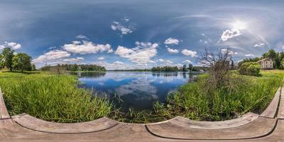 full seamless spherical hdri panorama 360 degrees  angle view on wooden pier of huge lake or river in sunny summer day and windy weather with beautiful clouds in equirectangular projection, VR content photo