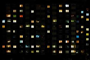 lapso nocturno de luz en las ventanas de un edificio de varios pisos. la vida en una gran ciudad foto