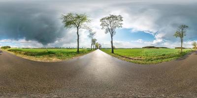 panorama completo esférico sin costuras vista de ángulo de 360 grados en carretera asfaltada sin tráfico entre callejones y campos con nubes impresionantes después de la lluvia en proyección equidistante equirectangular, contenido vr ar foto