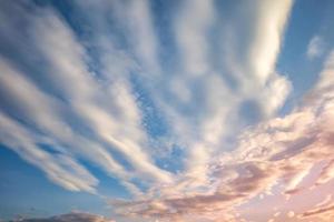 fondo de cielo azul con diminutas nubes de rayas rizadas por la noche. día despejado y buen tiempo ventoso foto