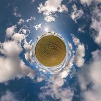 tiny planet in blue sky with sun and beautiful clouds. Transformation of spherical panorama 360 degrees. Spherical abstract aerial view. Curvature of space. photo