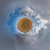 tiny planet in blue sky with sun and beautiful clouds. Transformation of spherical panorama 360 degrees. Spherical abstract aerial view. Curvature of space. photo