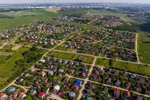 aerial panoramic view of green village with houses, barns and gravel road in forest photo