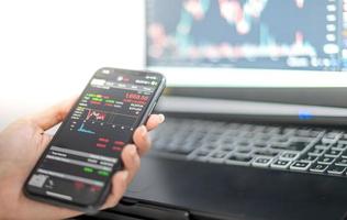 Female trader investor broker analyst holding a smartphone in hand analyzing stock market trading charts indexes data checking price using mobile stock market exchange application. photo