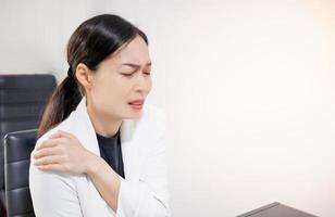 Asian young feeling painful from work, while sitting in front of the laptop in their home. Concept working woman office syndrome. photo