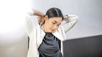 Asian young feeling painful from work, while sitting in front of the laptop in their home. Concept working woman office syndrome. photo