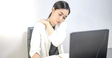 Asian young feeling painful from work, while sitting in front of the laptop in their home. Concept working woman office syndrome. photo