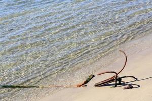 An old anchor is thrown on the seashore. photo