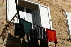 Washed linen dries on the street outside the window of the house. photo