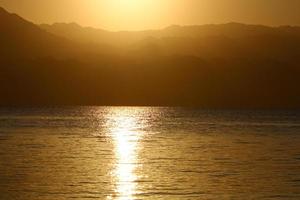 amanecer en el mar muerto en israel. el sol sale de detrás de las montañas en jordania. foto