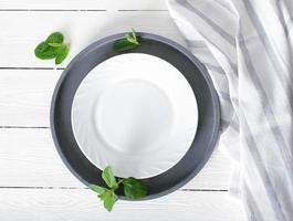 empty white plate on a table, dinner setting, mockup for food styling. tablecloth and cement round tray, top view photo