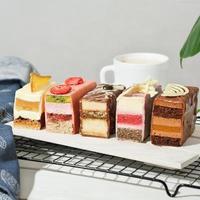 mini cakes with various fillings layered. cut cakes on a wooden board with fruit and chocolate decor. sweet dessert for wedding or birthday table, summer delisious treats. photo