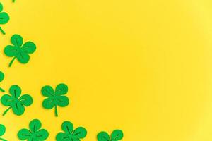 St Patricks Day background. Simply minimal design with green shamrock. Clover leaves isolated on yellow background. Symbol of Ireland. Lucky fortune wish concept. Flat lay top view layout copy space. photo