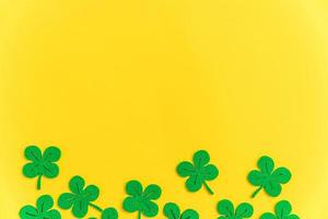 St Patricks Day background. Simply minimal design with green shamrock. Clover leaves isolated on yellow background. Symbol of Ireland. Lucky fortune wish concept. Flat lay top view layout copy space. photo