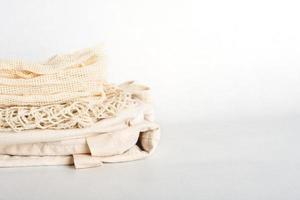 stack of eco friendly bags on a grey background. String and canvas bags made of cotton threads. Zero waste lifestyle. eco shoppers. reusable sustainalbe shopping. Copy space. photo