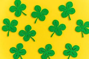 St Patricks Day background. Simply minimal design with green shamrock. Clover leaves isolated on yellow background. Symbol of Ireland. Lucky fortune wish concept. Flat lay top view layout copy space. photo