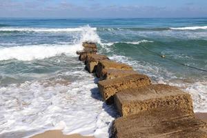 rompeolas en la playa de la ciudad para protegerse de las olas del mar. foto