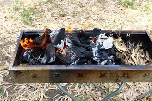 Coals are burning in a brazier in a forest clearing. photo