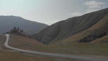 vista aérea do carro preto dirigindo em direção à atração turística - mosteiro da trindade gergeti na colina. viajar no conceito de kazbegi video