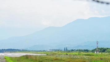 Isolated airport behind wired fence with no plane on runway and mountains background video