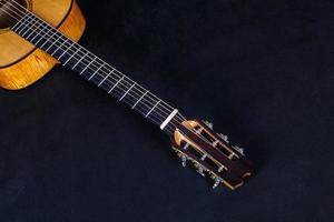 clavijas de afinación en la cabeza de la máquina de madera de cuello de guitarra acústica de seis cuerdas sobre fondo negro foto