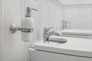 inodoro y detalle de un bidé de ducha de esquina con dispensadores de jabón y champú en el accesorio de ducha de montaje en pared foto