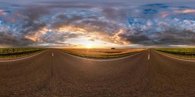 panorama hdri esférico completo sin costuras vista en ángulo de 360 grados en la carretera asfaltada entre campos en la puesta de sol de la tarde de verano con nubes impresionantes en proyección equirectangular, listo para la realidad virtual vr ar foto