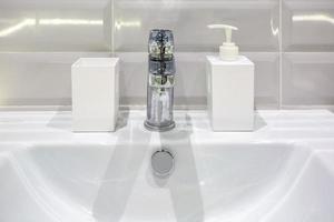 dispensadores de jabón y champú cerca del lavabo del grifo de cerámica con grifo en el costoso baño de loft foto