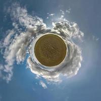 tiny planet in blue sky with sun and beautiful clouds. Transformation of spherical panorama 360 degrees. Spherical abstract aerial view. Curvature of space. photo