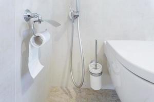 toilet and detail of a corner shower bidet with toilet paper holder on wall mount shower attachment photo