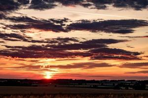 Blue red sky background with evening fluffy curly rolling clouds with setting sun. Good windy weather photo