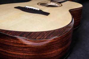 Tuning pegs on wooden machine head of six strings acoustic guitar neck on black background photo