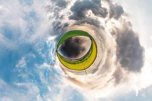 pequeño planeta transformación de panorama esférico 360 grados. vista aérea abstracta esférica en el campo en una agradable velada con impresionantes nubes hermosas. curvatura del espacio. foto