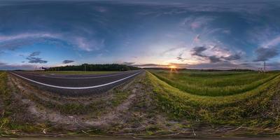 vista de ángulo de 360 grados de hdri esférico transparente cerca de la carretera asfaltada entre los campos en la puesta de sol de la tarde de verano con nubes impresionantes en proyección equirectangular, contenido de realidad virtual listo vr ar foto