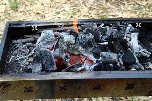 Coals are burning in a brazier in a forest clearing. photo