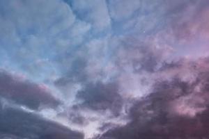 Blue sky background with evening fluffy curly rolling altocumulus altostratus clouds with setting sun. Good windy weather photo