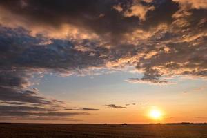 Blue red sky background with evening fluffy curly rolling clouds with setting sun. Good windy weather photo