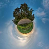 Little planet transformation of spherical panorama 360 degrees. Spherical abstract aerial view in field in nice evening with awesome beautiful clouds. Curvature of space. photo