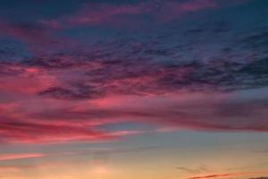 Blue violet red sunset sky background with evening fluffy curly rolling cirrostratus clouds. Good windy weather photo