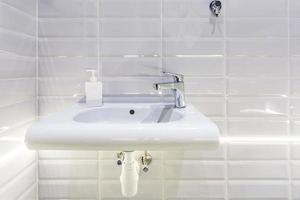 Soap and shampoo dispensers near Ceramic Water tap sink with faucet in expensive loft bathroom photo