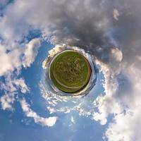 tiny planet in blue sky with sun and beautiful clouds. Transformation of spherical panorama 360 degrees. Spherical abstract aerial view. Curvature of space. photo