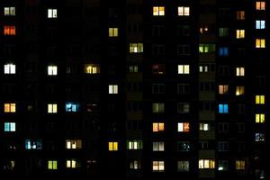 lapso nocturno de luz en las ventanas de un edificio de varios pisos. la vida en una gran ciudad foto
