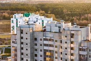 vista panorámica sobre la construcción de la nueva torre del barrio edificio alto de varios pisos sin terminar desde una vista de pájaro con bosque en el fondo foto